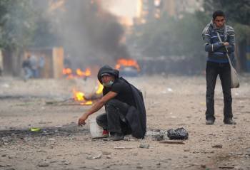 Dos manifestantes aguardan impávidos en medio de una calle, durante los enfrentamientos con la policía y soldados en las proximidades de la Plaza Tahrir (Foto: EFE)