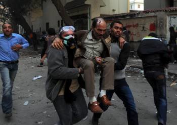Dos manifestantes trasladan a un herido en los enfrentamientos. (Foto: M. OMAR)