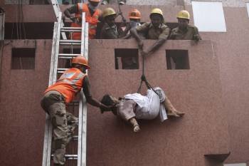 Trabajadores de los equipos de rescate evacúan el cuerpo sin vida de una pacienta del hospital de AMRI en Calcuta (India)  (Foto: EFE)