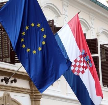 Banderas de Croacia (dcha) y la Unión Europea (izda) ondean en un edificio gubernamental en Zagreb  (Foto: EFE)