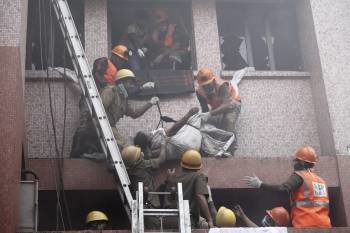 Trabajadores de los equipos de rescate evacúan el cuerpo sin vida de una paciente del hospital de AMRI en Calcuta (India)
