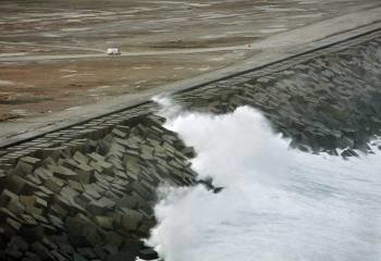 En la imagen, una furgoneta circula por una de las pistas del Puerto Exterior de A Coruña mientras una ola rompe contra el dique de abrigo. EFE/ Cabalar
