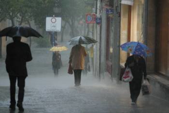 Varias personas se protegen con paraguas en un día de intensa lluvia en Ourense (Foto: JOSÉ PAZ)