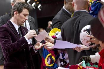 El delantero argentino del FC Barcelona Lionel Messi (i) firma autógrafos en la alfombra roja antes de la gala del Balón de Oro de la FIFA 2011 en el palacio de congresos de Zúrich (Foto: EFE)