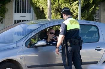 Un policía local practica una prueba de alcoholemia a un conductor en un control en una vía urbana.