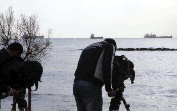 Un par de cámaras de televisión graban la costa desde el puerto de Limasol (Chipre) hoy, miércoles 11 de enero de 2012. Chipre autorizó hoy a zarpar a un buque que transporta una 'carga peligrosa' (Foto: EFE)