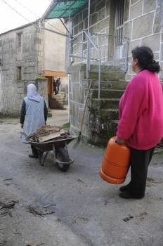Dos vecinas cargan una bombona de butano y leña. (Foto: MARTIÑO PINAL)