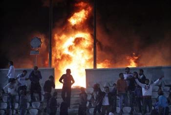 Jóvenes egipcios se alejan de un fuego provocado en el estadio Cairo hoy, miércoles 1 de febrero de 2012 después de la cancelación del juego de fútbol entre los equipos Zamalek y Ismaily (Foto: EFE)