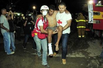 Un preso herido es trasladado por dos operarios de los equipos de rescate hondureños. (Foto: GUSTAVO AMADOR)
