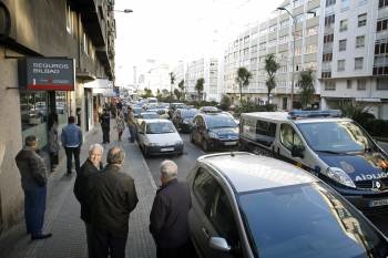 Vecinos y varios coches de policía, junto al lugar donde dos personas han resultado heridas esta tarde en A Coruña tras registrarse un tiroteo en el número 78 de la Avenida de Arteixo. (Foto: EFE)