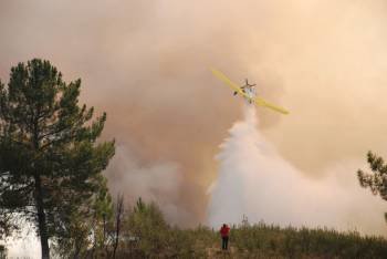 Una avioneta intenta sofocar con agua las llamas del incendio en el parque natural de Rubiá. (Foto: LUIS BLANCO)