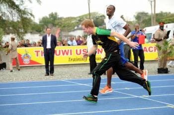El príncipe Enrique de Inglaterra (adelante), compite con el atleta jamaiquino Usain Bolt (atrás).