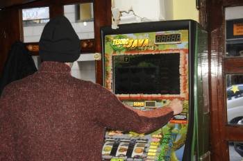 Un jugador, en la imagen, introduce una moneda en una máquina tragaperras en una cafetería de la ciudad.  (Foto: MARTIÑO PINAL)