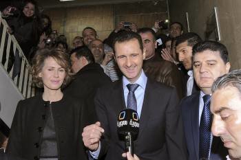 El presidente sirio, Bachar Al Asad (c), compareciendo ante la prensa junto a su esposa, Asma (i), después de votar en el referéndum sobre la nueva constitución.EFE