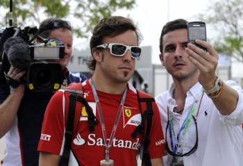 El piloto español de Fórmula Uno Fernando Alonso (centro), de la escudería Ferrari, se toma una fotografía con un fan durante la tercera sesión de entrenamientos en el circuito de Sepang (Foto: EFE)