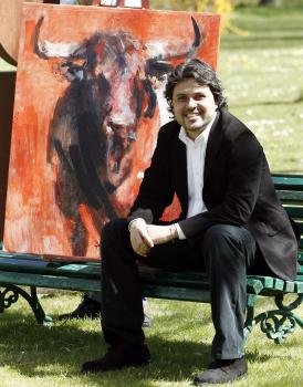El pintor colombiano Diego Ramos Ramírez (Cali, 1976), posa junto a su cuadro que anunciará la Feria del Toro de Pamplona.