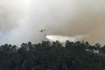 Un helicóptero echa agua sobre el bosque en llamas de las Fragas. (Foto: KIKO)