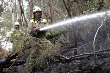 Miembros de una brigada forestal refrescan una zona de las Fragas do Eume afectada por el incendio. (Foto: KIKO DELGADO)