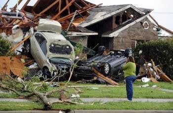 Una mujer habla por teléfono a las afueras de su casa, tras el paso de un tornado en Lancaster, Texas. EFE/LARRY W. SMITH