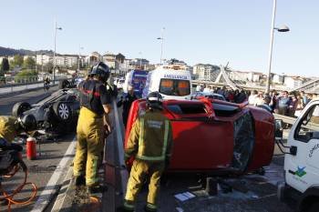 Estado en el que quedaron los dos turismos tras colisionar en el puente Ribeiriño de la ciudad. Los bomberos rescatan a uno de los heridos. (Foto: XESÚS FARIÑAS)