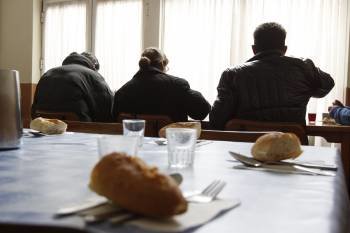 Dos hombres y una mujer comen en el comedor social de la ciudad en el primer turno, al filo de las 12.30 horas.  (Foto: XESÚS FARIÑAS)
