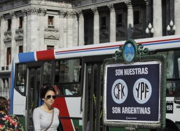Una  mujer camina en Buenos Aires junto a un cartel de apoyo a la expropiación de YPF.