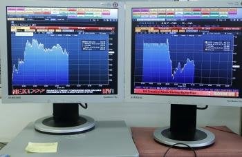 Imagen de dos pantallas de ordenador en el palacio de la Bolsa de Madrid que indican la evolución del IBEX 35 y de la prima de riesgo (Foto: EFE)