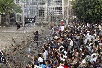 Un grupo de manifestantes intenta saltar una barricada cerca del Ministerio de Defensa, en El Cairo, Egipto.