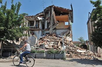 Un ciclista pasa por delante de un edificio dañado en Rovereto, Módena, tras el terremoto. (Foto: M. DEGL'INNOCENTI)