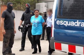 Efectivos de los Mossos d' Esquadra conducen al furgón policial a una de las detenidas en la operación contra el tráfico de drogas que se lleva a cabo desde primeras horas de esta mañana en el barrio de Can Espinós de Gavà.