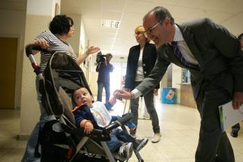 El conselleiro de Educación, Jesús Vázquez, saluda a un bebé en Padrenda. (Foto: MARCOS ATRIO)