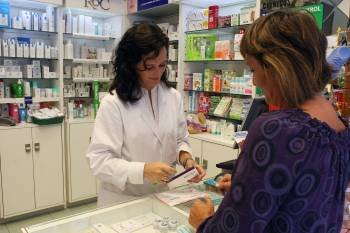 Una farmacéutica, dispensando un medicamento a una cliente (Foto: ALBERT OLIVÉ)