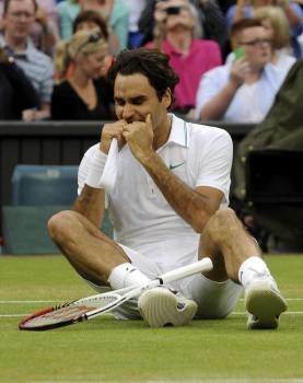 Federer celebra tirado en la hierba de Wimbledon la séptima victoria en el torneo londinense. (Foto: GERRY PENNY)