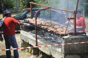 Dous cociñeiros preparan unha enorme parrilla de chuletóns á brasa, na festa de Garabás.