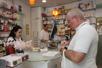 Un usuario de una farmacia guarda su tarjeta sanitaria y se dispone a pagar por sus medicamentos. (Foto: XESÚS FARIÑAS)