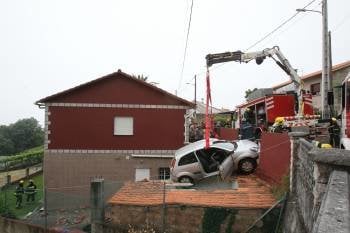 Una grúa retira el automóvil del tejado. (Foto: ALBERTE)