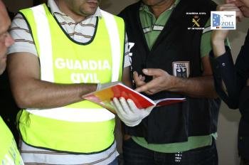 Fotografía facilitada por la Guardia Civil de varios agentes observando un cuaderno tras la detención de un presunto traficante de drogas holandés