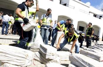 Varios agentes descargan en el puerto de Cádiz la importante cantidad de cocaína hallada a bordo de un mercante