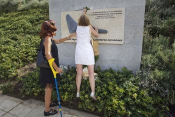 Dos componentes de la Asociación de Afectados del Vuelo JK5022 colocan una rosa blanca en el monumento a los fallecidos situado en 'La Rosaleda' 