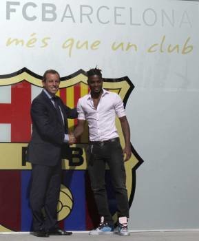 El futbolista camerunés Song, ayer junto a Sandro Rosell y el escudo del Barcelona. (Foto: ALBERT OLIVÉ)