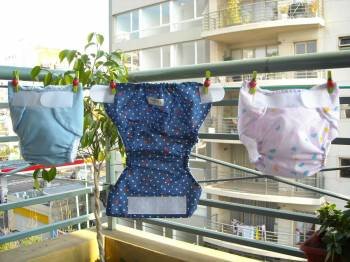 Dos nuevos modelos de pañales de tela, puestos a secar en el tendedero de un piso. 