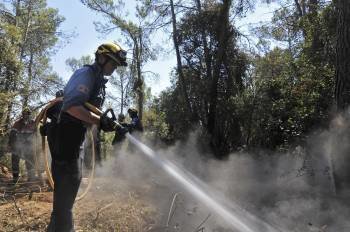 Un bombero remoja áreas calientes del bosque afectado por el incendio en Madremanya (Gerona), (Foto: R. TOWNSEND)