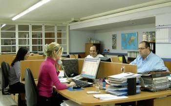 Un grupo de personas, ante sus puestos de trabajo en una oficina. 