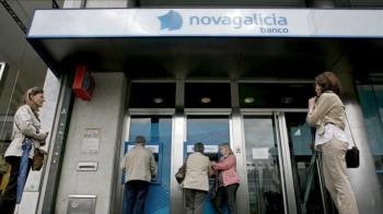 Varias personas esperan para sacar dinero de los cajeros de una sucursal de Novagalicia Banco. (Foto: EFE)