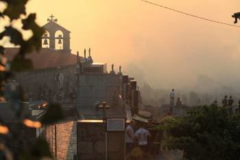 Efectivos contraincendios, en la imagen, trabajan en el fuego forestal declarado entre Rairo y Santa Mariña, al lado de una capilla. (Foto: JOSÉ PAZ )