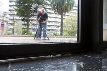 Un cámara toma imágenes de los desperfectos en la puerta del Club Financiero de Vigo. (Foto: SALVADOR SAS)