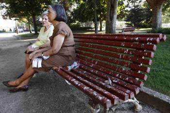 Una mujer se sienta sobre unos papeles para no mancharse con los excrementos de los estorninos. (Foto: XESÚS FARIÑAS)