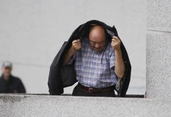 Francisco Fernández-Liñares se protege de la lluvia con una chaqueta, a la llegada al Juzgado. (Foto: ELISEO TRIGO)