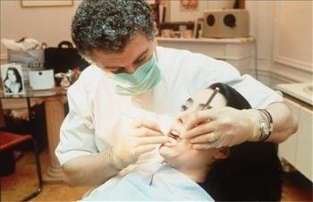 Un dentista realiza una revisión bucal a su paciente. 