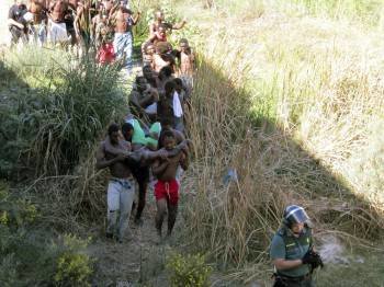 El grupo de subsaharianos avanza tras el asalto a la valla llevando a hombros a varios heridos. (Foto: NOELIA RAMOS)